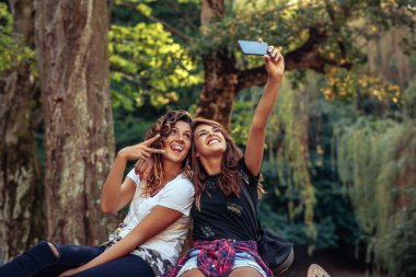 İki kız cep telefonu açık havada ile fotoğraf çekme eğleniyor.