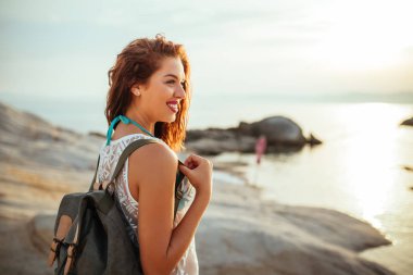 Genç bir kadın ile bir sırt çantası plaj keşfetmek atış.