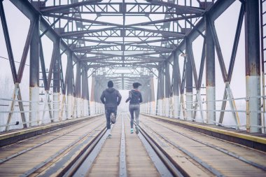 Köprüde kışın çalışan genç atlet çift.
