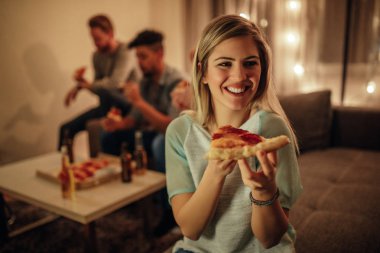 Bir dilim pizza onun elinde tutan güzel bir genç kadın.