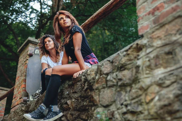 Twee Jonge Mooie Stedelijke Meisjes Zitten Een Muur Naast Hun — Stockfoto