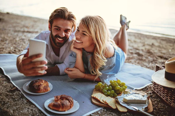 ピクニックに携帯電話で Selfie を取る若いカップルの写真 — ストック写真