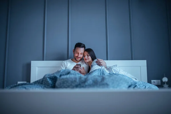 Happy Couple Cuddling Bed Browsing Mobile Phone — Stock Photo, Image