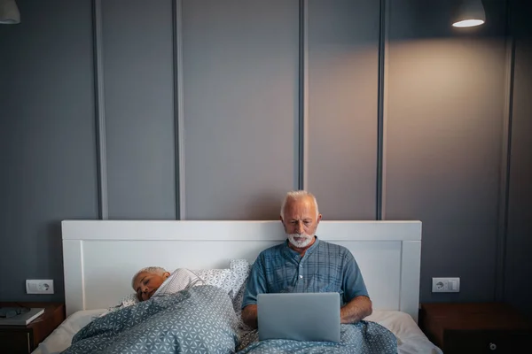 Mature Man Using Computer While Woman Taking Nap — Stock Photo, Image