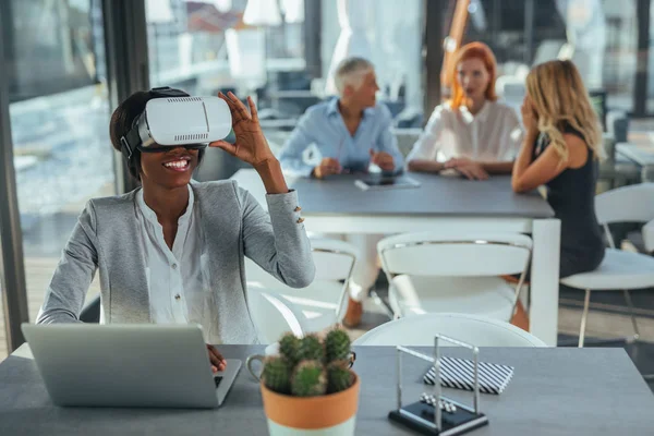 African american woman wearing VR headset while sitting in the office.