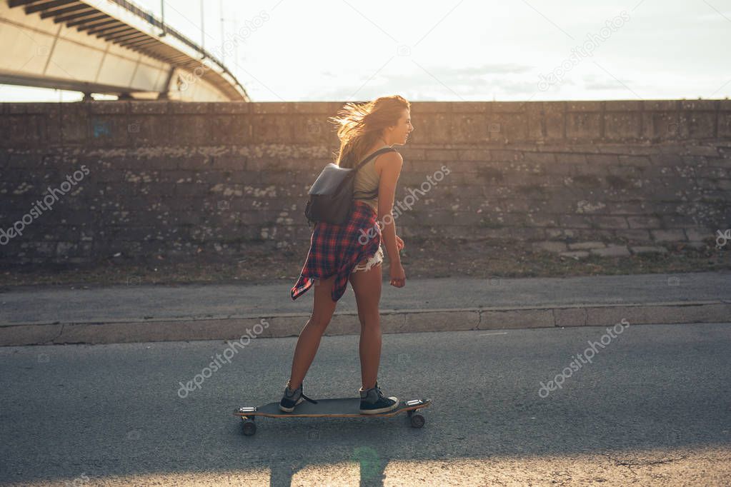 Happy teenager driving a longboard in the city.