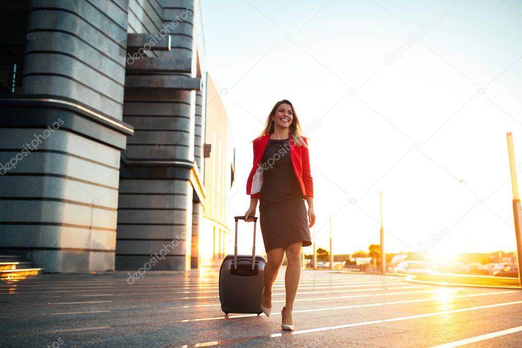 A young professional woman arriving at the airport and walking towards her car.