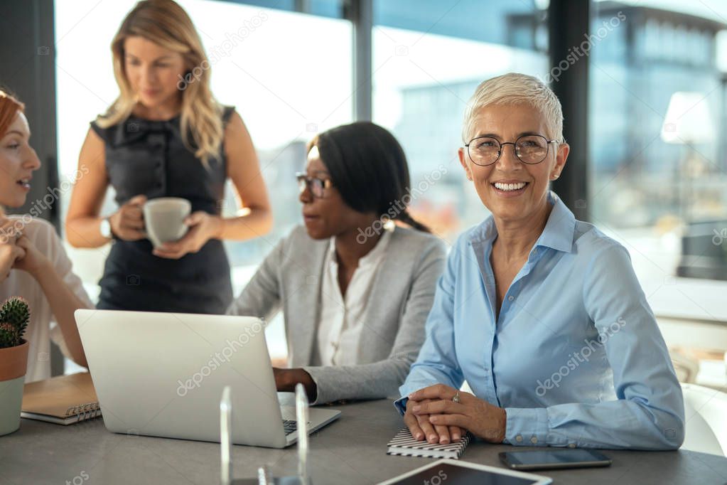 Group of female businesswomen working together on a laptop.