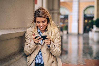 Soğuk bir sonbahar gününde telefonunu kullanan bir genç güzel kadın.