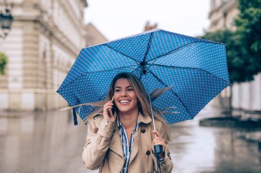 Güzel bir genç kadın yağmurlu şehirde yürürken ona telefon arkadaşları ile sohbet.