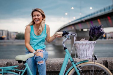 Nehir kenarında oturan genç gülümseyen bir kadın portresi.