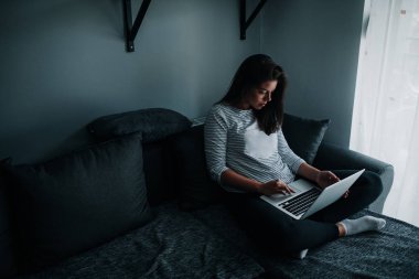 Güzel genç kadın evde dizüstü bilgisayarda yazarak.