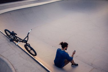 Genç bir adam onun telefon--dan iş üstünde onun Bmx hileci bir fren çekerken tarama.