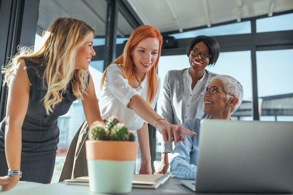 Team of businesswomen working on a laptop in a cafe.