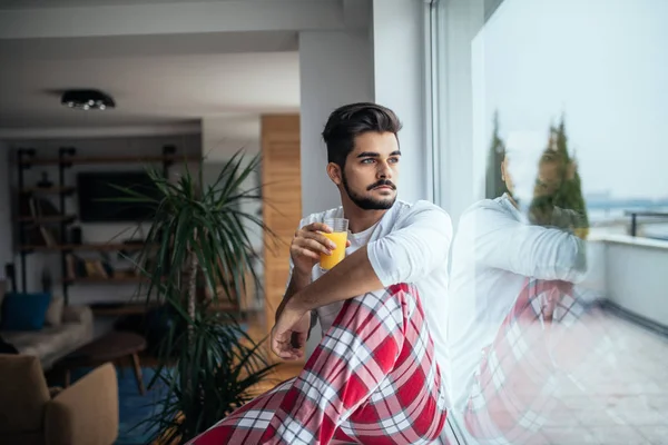 Retrato Joven Guapo Sentado Junto Ventana Apartamento Bebiendo Jugo Pijama —  Fotos de Stock