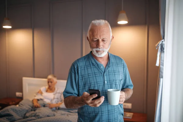 Старший Проверяет Телефон Наслаждаясь Утренним Кофе — стоковое фото
