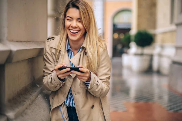 A young woman laughing as she is browsing her social media on her phone.