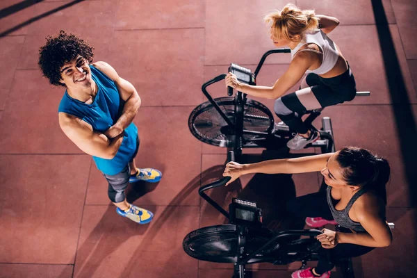 A young athletic trainer overlooking his clients during a workout.