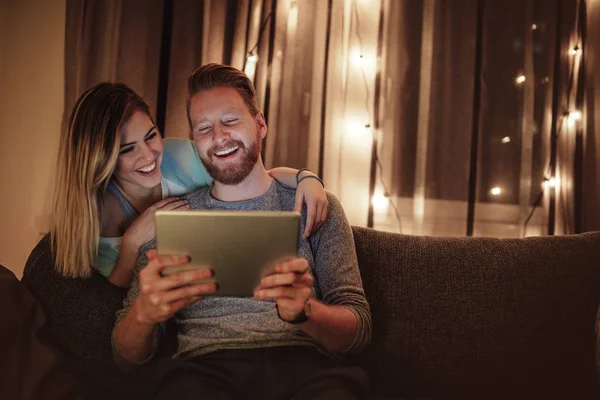 A young man and a woman enjoying a film on their tablet.