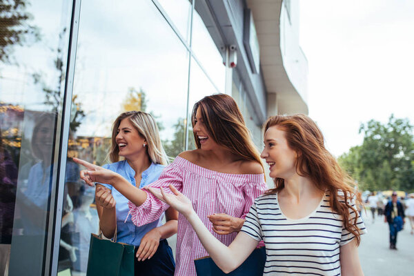 Photo of amazed young women pointing in the shop window.