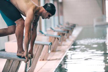 Atletik bir profesyonel yüzücü havuza atlamak için hazırlanıyor.