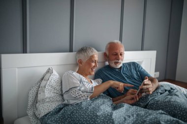 Üst düzey bir çift yatakta yatan ve onların telefon tarama.