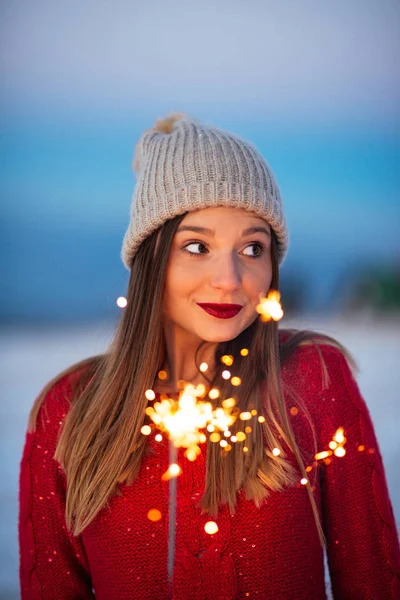 Close up portrait of a wonderful young woman holding a sparkling stick outdoors.