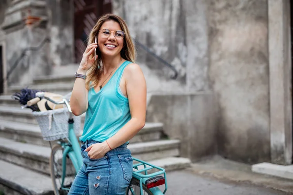 彼女の自転車アウトドアに頼っている間携帯電話で話している笑顔の若い女性の肖像画 — ストック写真