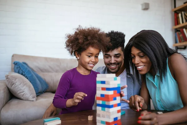 A happy black family palying a round of jenga with their lovely daughter.