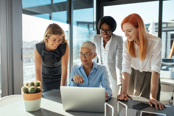 A group of professional women working together on a project in their office.