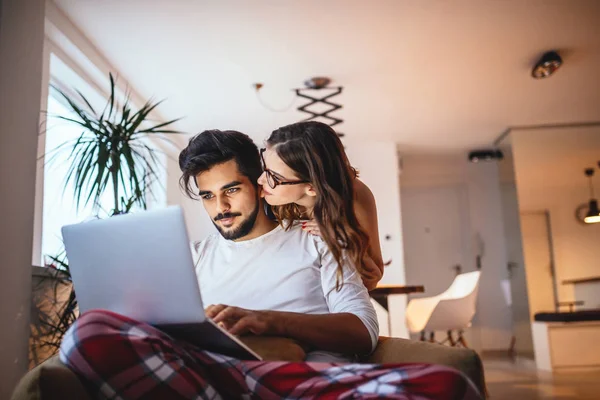 Photo Young Couple Embracing While Using Laptop Home — Stock Photo, Image