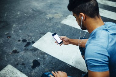 Onun cep telefonu kullanırken çömelmiş genç atlet