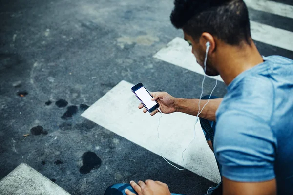 Young Athlete Crouching While Using His Mobile Phone — Stock Photo, Image