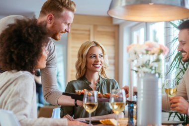 Dört kişi yemek yerken gülüyor