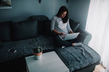 Oturma odasını içinde genç bir kadın mutlu bir şekilde onu laptop tarama.