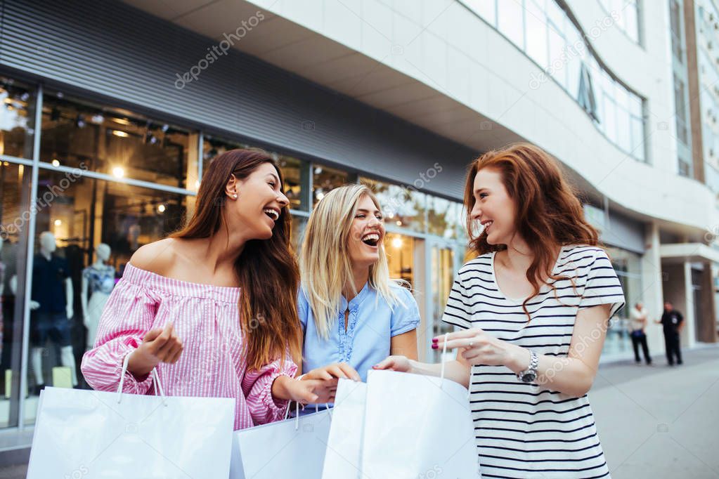 Three friends carrying shopping bags outdoors