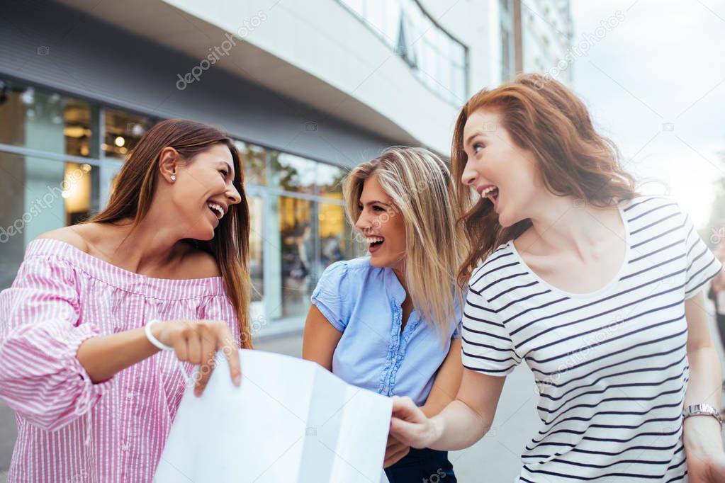 Three young women looking at a shopping bag
