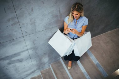 Kız alışveriş torbaları tutan bir masaj yazarak