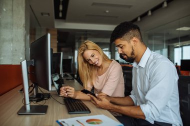 Genç erkek ve kadın bir ofiste bir cep telefonu bakarak