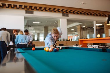 Genç adam ofis öğle arasında bilardo oynarken