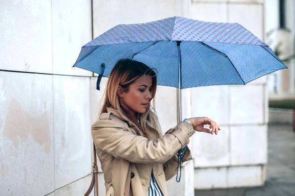 雨の日に彼女の腕時計を見て若い女性 — ストック写真