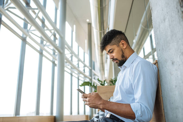 Shot of a young businessman using a mobile phone in the modern office space