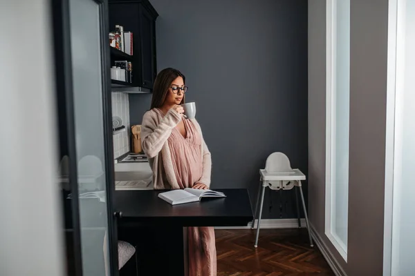 Hermosa Mujer Embarazada Leyendo Libro Tomando Café Casa — Foto de Stock