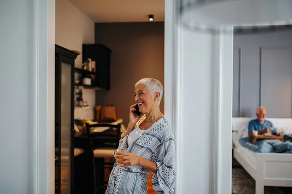 Пожилая Женщина Разговаривает Телефону Мужчина Заднем Плане Завтракает Постели — стоковое фото