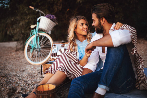 Young couple relaxing on the beach with a bicycle in the background