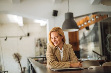 Onun masasında otururken gülümseyen çekici sarışın kadın.