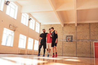 Ayakta ve sahada konuşmak üç basketbol oyuncu tam uzunlukta portresi.