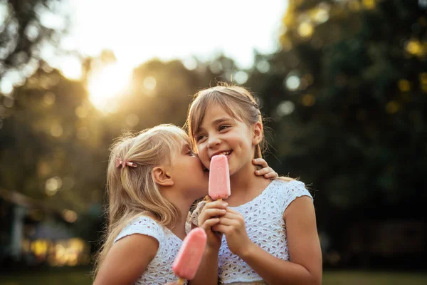 Tiro Duas Meninas Sussurrando Enquanto Comem Sorvete Livre Pôr Sol — Fotografia de Stock