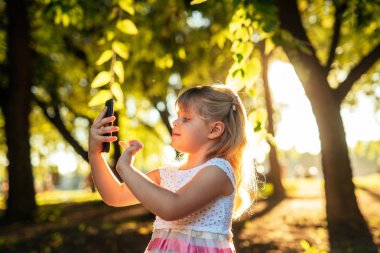 Genç kız kendini bir fotoğraf parkta günbatımında çekici..