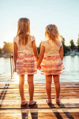 Arka görünümünde batımını bir iki kız.